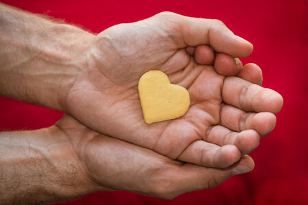 male hands holding biscuit heartの写真素材