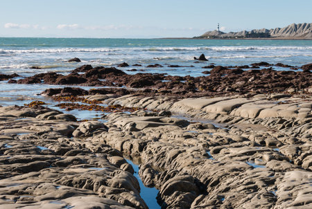 rocky coastline with lighthouse in distance