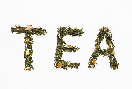 green tea with orange peel and chamomile on white backgroundの写真素材