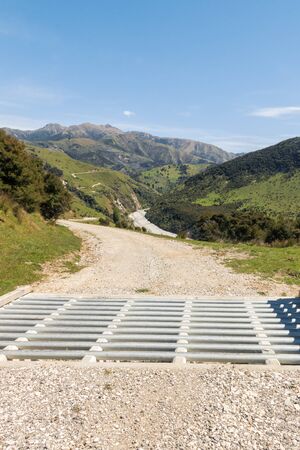 cattle grid with gravel road and rural New Zealand countryside in backgroundの写真素材