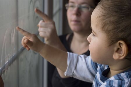Mom and two years old son paint on window の写真素材