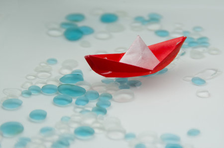 Red Origami Sail Boat floating in water