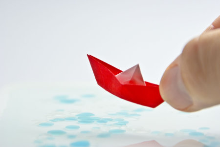 Red Origami Sail Boat floating in waterの写真素材