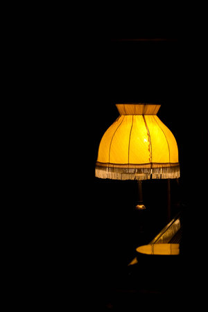 Desk lamp with the yellow lamp shade in the dark roomの写真素材