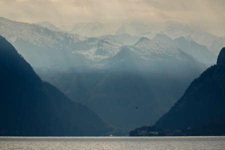 Sunlight getting through clouds and lighting the mountains surrounding the lakeの写真素材