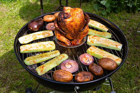Chicken carcass and vegetables baked and smoked on a charcoal grillの写真素材
