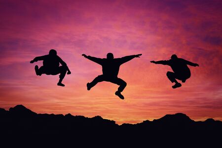 Three boys jump over a mountain sunsetの写真素材