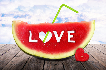 Fresh juicy watermelon slice with love letters on it standing on a table in the skyの写真素材