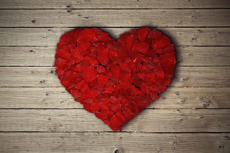 Rose petals arranged in shape of heart on wooden table.の写真素材