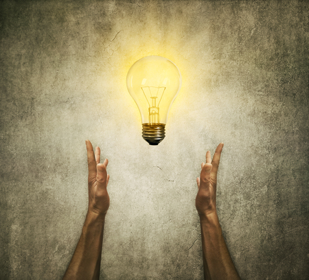Closeup of two human hands holding a light bulb. Creativity and idea conceptの写真素材