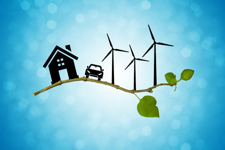 Environmental green energy concept. Silhouette of house, car and wind turbine on a tree branchの写真素材