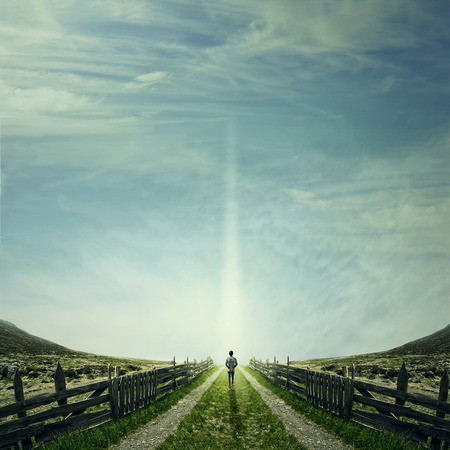 Man walking on a country road with a relax mood, following a light. Way of life conceptの写真素材