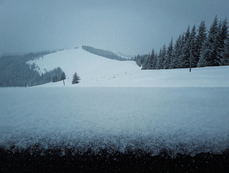 Wooden fence covered with snow on a beautiful mountains backgroundの写真素材