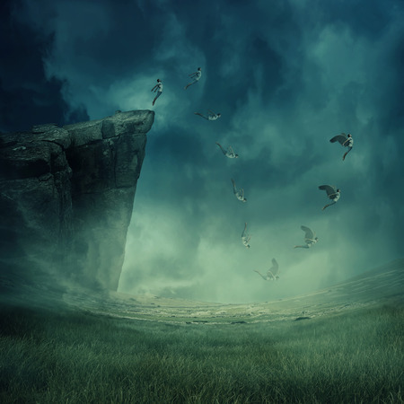 Young boy jumping from the edge of a cliff, falling down while his wings grow and help to fly. Astral travel, mystical rapture state psychokinesis condition. Magic soul energy show human illusion.の写真素材