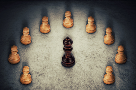 Black queen chess piece surrounded by white pawns joining their power together. Business group leadership and team working symbol.の写真素材