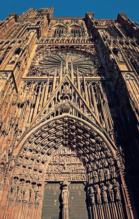 The Gate of Roman Catholic Cathedral Notre Dame of Strasbourg in Alsace, France. Beautiful sunny day with clear blue sky. Majestic gothic architecture.の写真素材