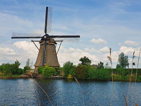 Old mill near a water canal at Kinderdijk Overwaard in the Netherlands. Windmill Unesco World Heritage with unique Dutch sight as popular tourist attraction in Holland.の写真素材