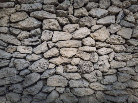 Irregular stone masonry wall background. Old limestone rocks of different size and shapes stacked carefully. Detailed texture of construction element. Antique rough manual workの写真素材