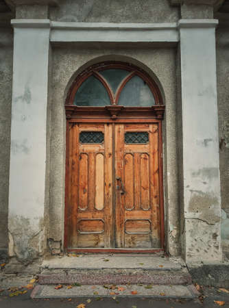 Vintage wooden door and weathered facade details of an old historical building. Outdoors architecture elements. Rustic doorwayの写真素材