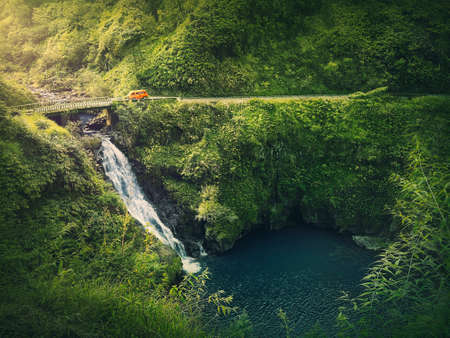 Upper Waikani Falls or Three Bears Waterfalls, the Road to Hana in Hawaii. Cascade in the jungle among tropical green vegetation. Wonderful scene in hawaiian dense rainforest with mixed fern plantsの写真素材