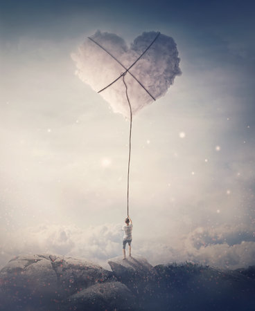 Romantic view of a young man, holding a lasso, trying to catch and pull a heart shaped cloud from the sky. Magical scene, love and romance conceptの写真素材