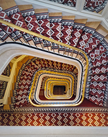 Abstract shape luxurious stairs with red carpet cover and golden handrail. Hypnotic pattern spiral...