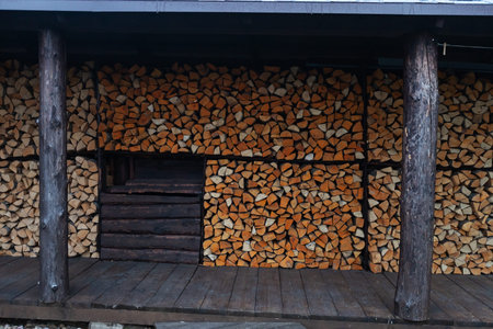 Firewood in a wooden house. Woodpile of firewood.
