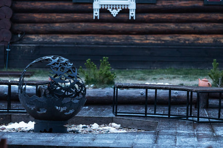 A black vase stands on the steps of a wooden house in the village.