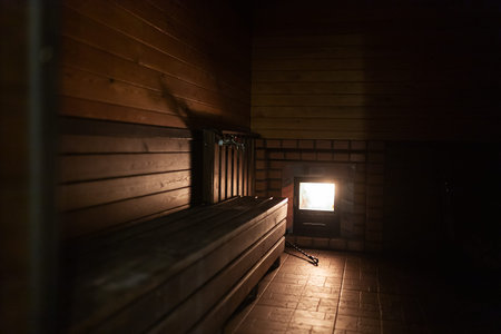 Wooden sauna in a dark room at night with a glowing lamp