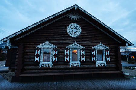 Wooden house in the village in the evening. Decorated with white ornaments.の写真素材