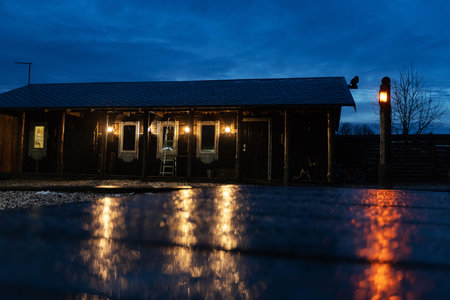 Old wooden house in the village at night with reflection in the water