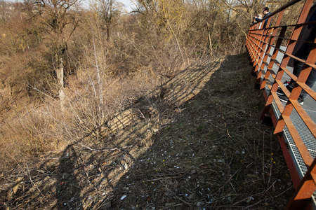 a steep slope near observation platform in mountains, natural landscape is spoiled by people, on the dry grass in early spring in Sunny weather lie cigarette butts and garbage left by touristsの写真素材