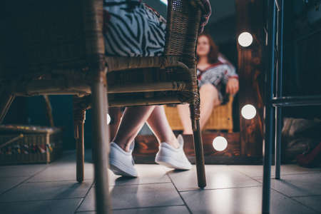 Close up photo of two girls sitting on chair and looking at each otherの写真素材