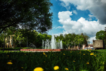 Fountain in the city park on a background of blue sky with cloudsの写真素材