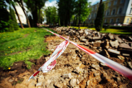 Close-up of a red tape with a white stripe on the background of the ruins of the building.の写真素材