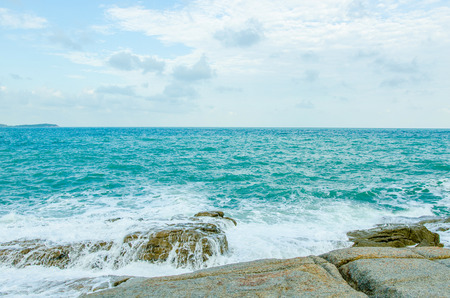 Sea waves are bouncing rocks into white foam.の写真素材