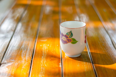 A tea cup is located on the wooden floor.