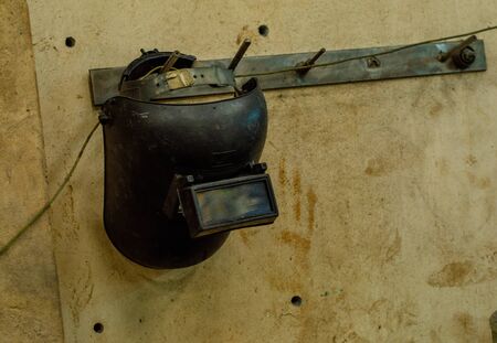 Steel welding mask hanging on the wall of the room.の写真素材