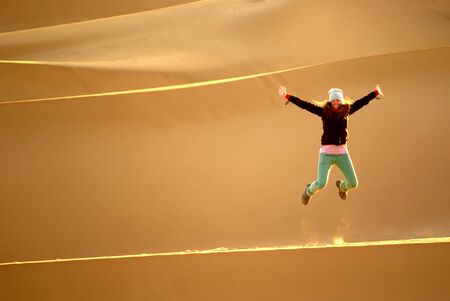 Happy woman leaping on the dunes in the Sahara desertの写真素材