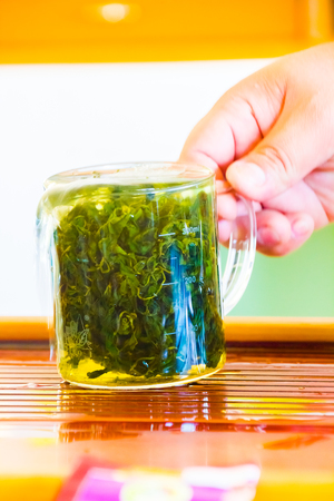 Freshly prepared green oolong tea with leaves in water of a glassの写真素材