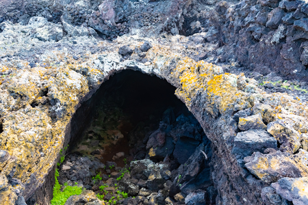 Vulcanic tunnel cave in the Lava field near to tourist walking road to vulcano Caldera Blanca, Lanzarote, Canary Islands, Spain.の写真素材