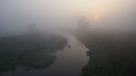 The rising sun seen through the autumn fogの写真素材
