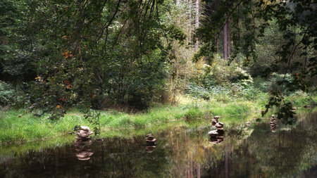 September in Sudetes, piles of stones in the river, forest, trees and reflections in the waterの写真素材