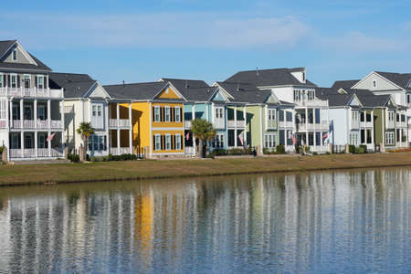 Brightly Colored Houses Reflected in a Pond in a Suburban Neighborhoodの写真素材