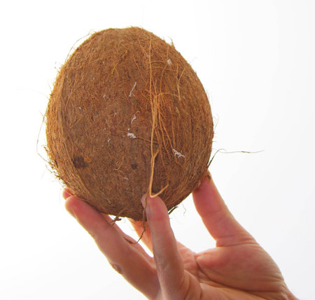 A hand grasping a coconut with a white background