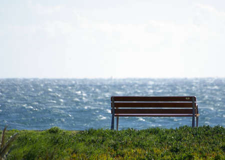 An iron and wooden bench overlooking the Mediterranean seaの写真素材