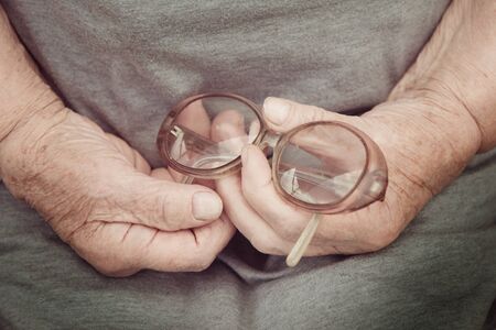 old woman's hands holding glassesの写真素材