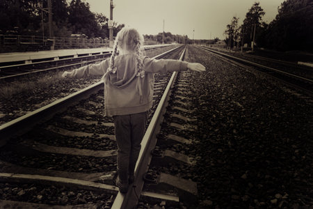 a five-year-old girl is walking on the tracks. dark tinted