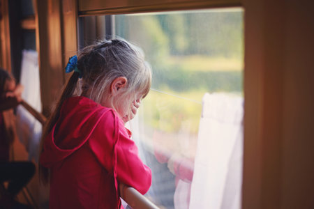 five-year-old girl looks out the window of the train and cryの写真素材