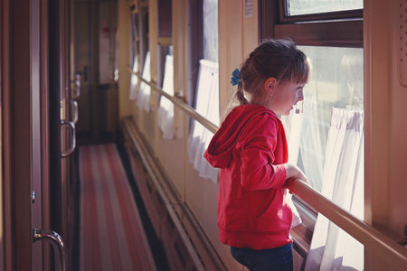 five-year-old girl looks out the window of the train